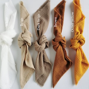 Può includere: Cinque quadrati di tessuto annodati, mostrati su uno sfondo bianco. I quadrati sono dei seguenti colori: bianco, beige, beige scuro, marrone e giallo ocra.