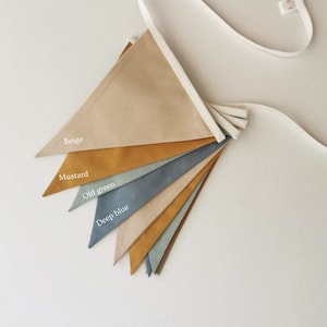 May include: A beige, mustard, old green, deep blue, and light blue fabric bunting with a white string.