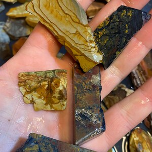 Puede incluir: Surtido de losas de piedra natural pulidas, multicolores. Las losas tienen una variedad de patrones y texturas, incluyendo rayas, remolinos y motas. Los colores incluyen marr&oacute;n, dorado, negro y rojo.