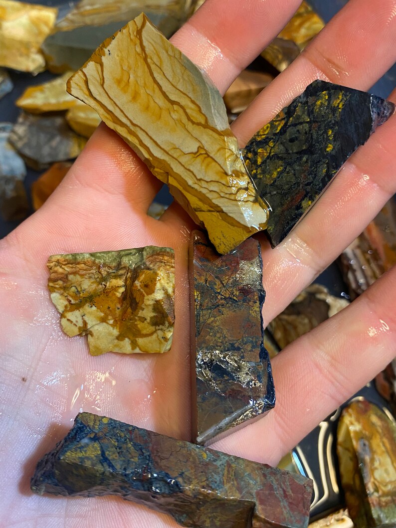 Puede incluir: Surtido de losas de piedra natural pulidas, multicolores. Las losas tienen una variedad de patrones y texturas, incluyendo rayas, remolinos y motas. Los colores incluyen marr&oacute;n, dorado, negro y rojo.