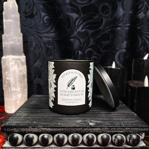May include: Black candle jar with a white label that reads "Petals & Plumes" and "Atramentum Scriptorium" with the scent "Black Ink & Patchouli".