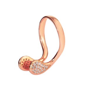 Puede incluir: Un anillo de oro rosa con un diseño curvo único. El anillo está adornado con pequeñas piedras preciosas transparentes.