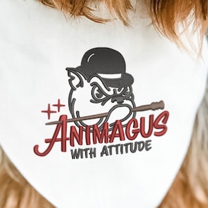 Puede incluir: Un pañuelo blanco con un bulldog rojo y negro que lleva un bombín y sostiene una varita. El texto dice "Animgus with Attitude". El pañuelo lo lleva un perro pequeño marrón y blanco.