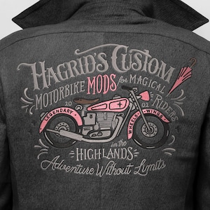 Pode incluir: Casaco cinza escuro com um design bordado com uma motocicleta rosa e o texto "Hagrid's Custom Motorbike Mods for Magical Riders". O design inclui as palavras "Legendary", "Wings" e "Adventure Without Limits".