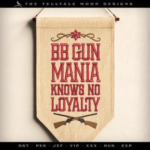 May include: A beige banner with red embroidered text that reads "BB GUN MANIA KNOWS NO LOYALTY". The banner has a brown star and two crossed red and brown toy guns.