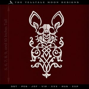 May include: White embroidered design featuring a bat skull with Celtic knotwork and scroll details. The design is approximately 5 to 10 inches tall. The text "THE TELLTALE MOON DESIGNS" is at the top.