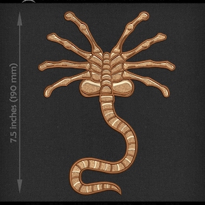 May include: A tan-colored embroidered design of an alien facehugger, measuring 7.5 inches (190 mm) in height. The design features a detailed, segmented body with multiple appendages. The text "DESIGNS FOR DOWNLOAD" is at the top.