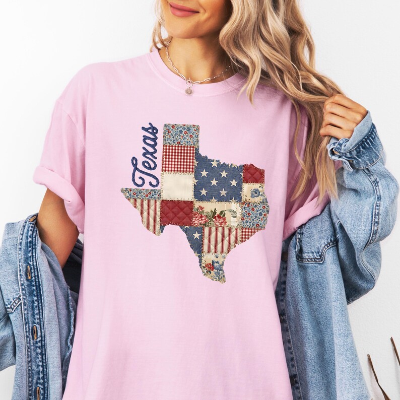 May include: A light pink t-shirt featuring a patchwork design of the state of Texas. The Texas outline is filled with various patterns, including stars, stripes, and floral prints. The word "Texas" is written in a cursive font.