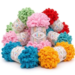 Pode incluir: Uma coleção de novelos de lã Alize Puffy em várias cores, incluindo rosa, vermelho, amarelo, azul-petróleo e verde-claro. Cada novelo apresenta um rótulo de papel central com a marca Alize Puffy impressa numa fonte estilizada sobre um fundo às riscas.