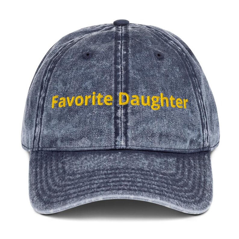 Op de afbeelding: Een denimblauwe baseballcap met de geborduurde tekst "Favorite Daughter" in geel. De cap heeft een gebogen klep en een verstelbare band aan de achterkant. Een klassieke stijl, geschikt voor vrijetijdskleding.