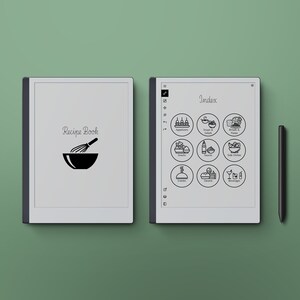 Puede incluir: Un lector electrónico en blanco y negro con una cubierta blanca que dice "Recipe Book" y un icono de batidor y tazón. El lector electrónico está abierto en una página con la palabra "Index" y iconos para diferentes tipos de recetas.