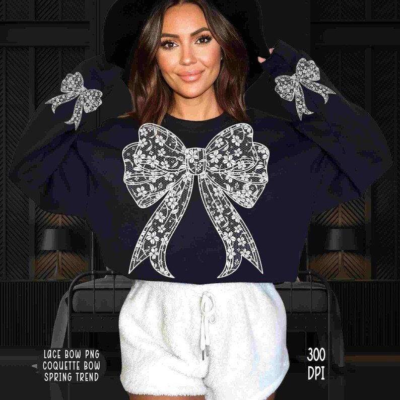 Puede incluir: Una sudadera negra con un gran dise&ntilde;o de lazo de encaje blanco. La sudadera es corta y tiene mangas largas. La modelo lleva pantalones cortos blancos y un sombrero negro.
