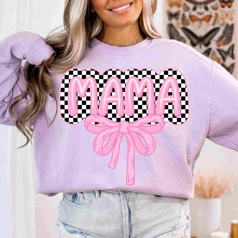 May include: A lavender sweatshirt with a pink checkered graphic that says "MAMA" with a pink bow underneath.