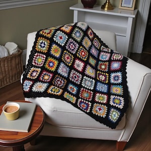 May include: A colorful, handmade crochet blanket with a black border. The blanket is made of numerous squares in various colors, including blue, yellow, red, and green. The blanket is draped over a white armchair, creating a cozy and inviting look.