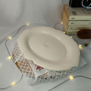 Kleines Tablett, kleine Schale, leere Tasche aus handgefertigtem Steingut in glänzendem Naturbeige mit einem Engel