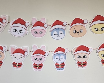 May include: A Christmas banner with 14 festive characters wearing Santa hats. The characters are a mix of animals, including cats, dogs, and rabbits, and a few are human-like. The banner is strung with red and white string.