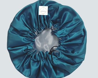 Può includere: Un copricapo da notte in raso turchese con chiusura a coulisse. Il copricapo è foderato in argento e ha un piccolo cartellino quadrato con la parola "JOYOUS" stampata su di esso.