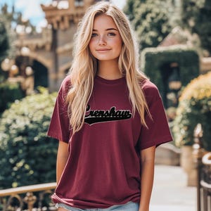 May include: A maroon t-shirt with a black vintage-style graphic that says "Crenshaw".