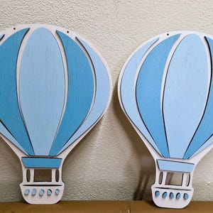 Puede incluir: Dos globos aerostáticos de madera azul y blanco con un diseño a rayas. Los globos están colgados del techo.