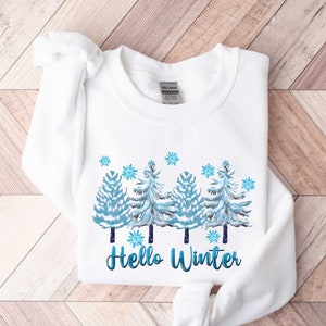 May include: White sweatshirt with a winter-themed design featuring three blue and white trees with snowflakes and the text "Hello Winter".