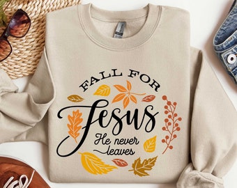 May include: Beige sweatshirt with a fall-themed graphic that says "Fall for Jesus He never leaves". The graphic features orange, red, and yellow leaves.
