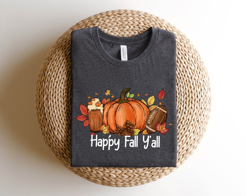May include: A dark gray t-shirt with a graphic design of a pumpkin, football, and a fall-themed drink. The text "Happy Fall Y'all" is printed below the graphic.