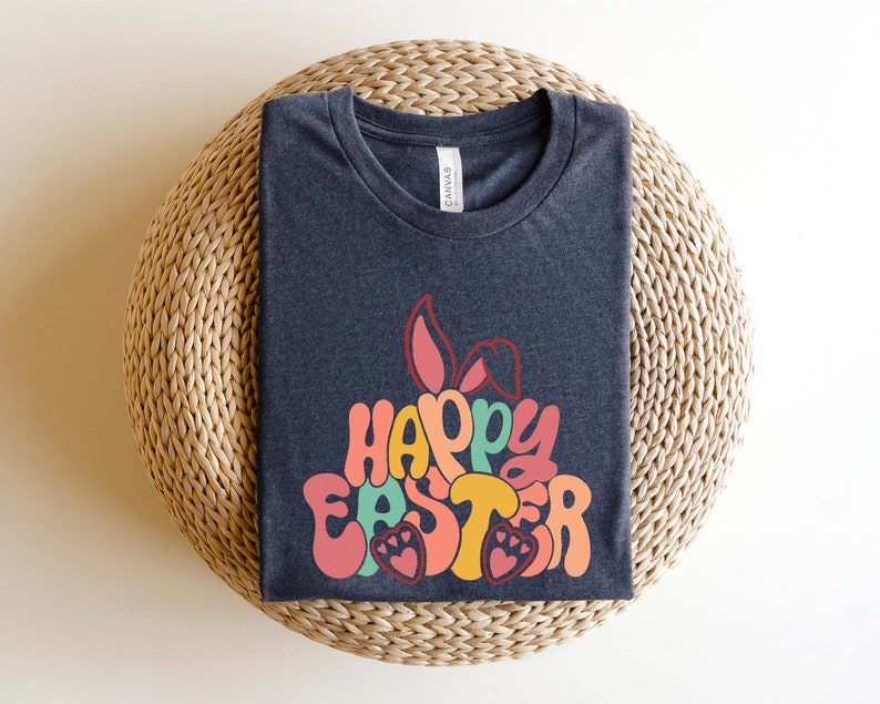 May include: A dark gray t-shirt with a colorful graphic design that says "Happy Easter" with bunny ears. The graphic is in a retro style with a rainbow color scheme.