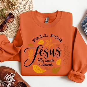 May include: Orange sweatshirt with the text "Fall for Jesus He never leaves" surrounded by fall leaves.
