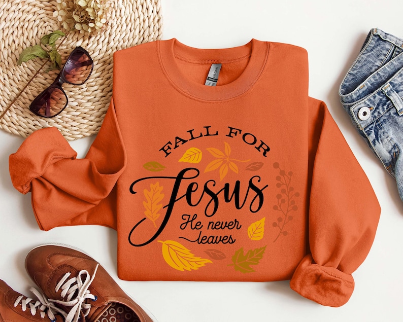 May include: Orange sweatshirt with the text "Fall for Jesus He never leaves" surrounded by fall leaves.