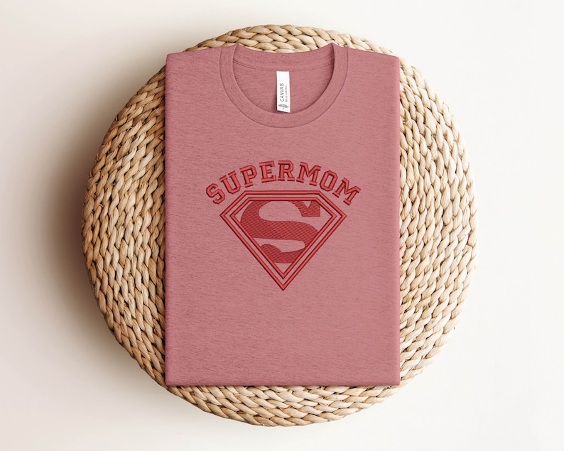 May include: A pink t-shirt with the text "SUPERMOM" and a red Superman logo.