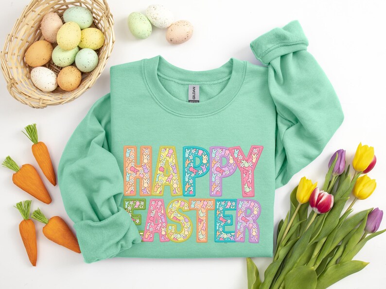 May include: A mint green sweatshirt with the words "Happy Easter" in colorful letters made up of small bunny and flower designs.
