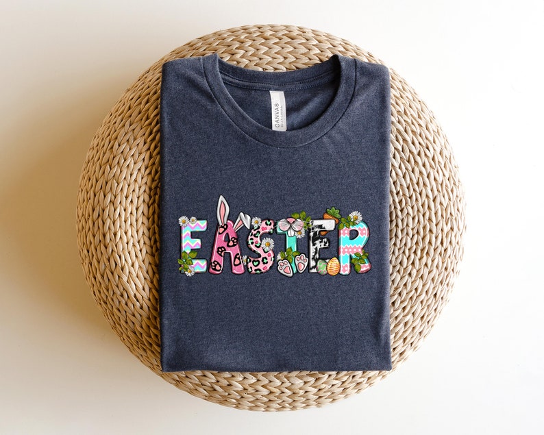 May include: A dark gray t-shirt with the word "Easter" printed on the front. The letters are decorated with colorful patterns, including animal print, stripes, and polka dots.