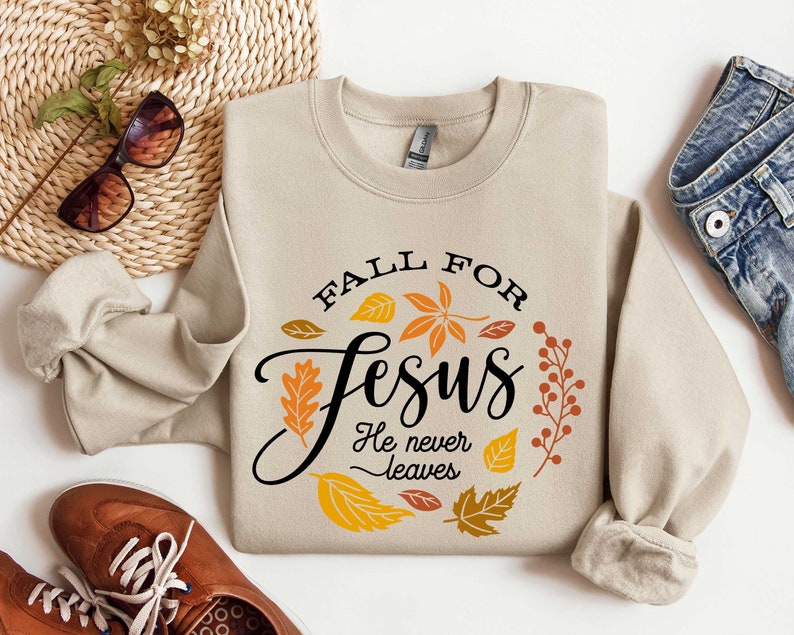 May include: Beige sweatshirt with a fall-themed graphic that says "Fall for Jesus He never leaves". The graphic features orange, red, and yellow leaves.
