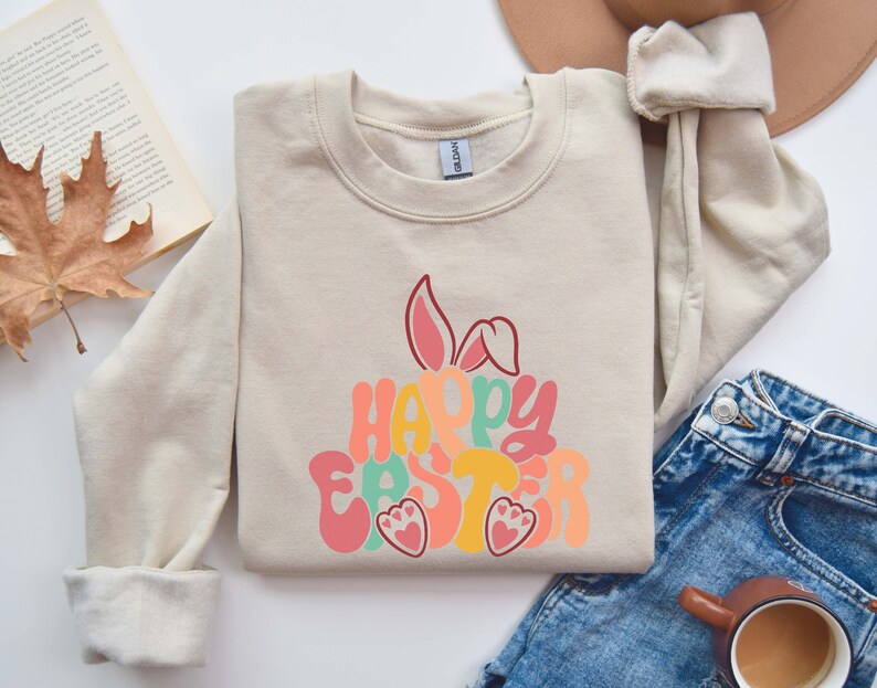 May include: A beige sweatshirt with a colorful "Happy Easter" graphic featuring a bunny silhouette and paw prints.