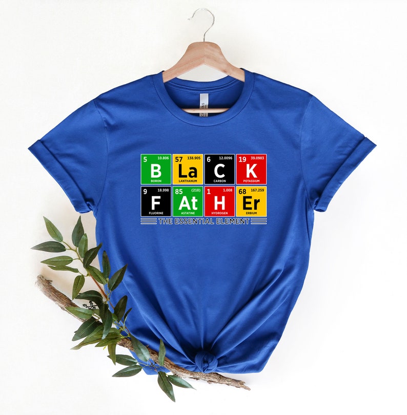 Op de afbeelding: Een koninklijk blauw t-shirt met een afbeelding van het periodiek systeem van de elementen die "Black Father" spellen met de tekst van het essenti&euml;le element eronder.