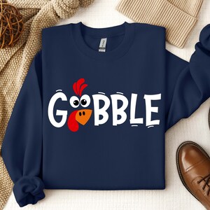 May include: A navy blue sweatshirt with a white graphic of a turkey head and the word "GOBBLE".