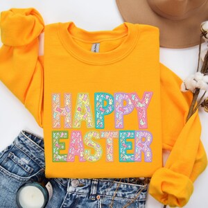May include: A yellow sweatshirt with the text "HAPPY EASTER" in rainbow colors with a floral pattern. The letters are outlined in black.