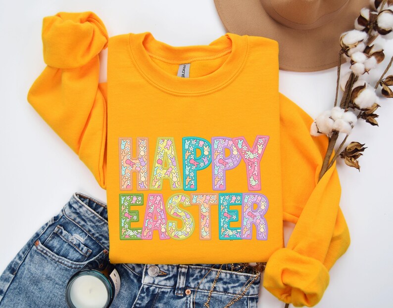 May include: A yellow sweatshirt with the text "HAPPY EASTER" in rainbow colors with a floral pattern. The letters are outlined in black.