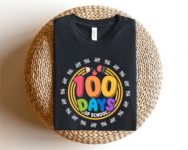 May include: A black t-shirt with a colorful graphic that says '100 Days of School' surrounded by a circle of yellow hash marks. The number 100 is in rainbow colors and the words 'Days of School' are in a rainbow gradient.
