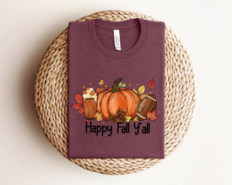 May include: A maroon t-shirt with a graphic of a pumpkin, a football, and a glass of beer with the text "Happy Fall Y'all".