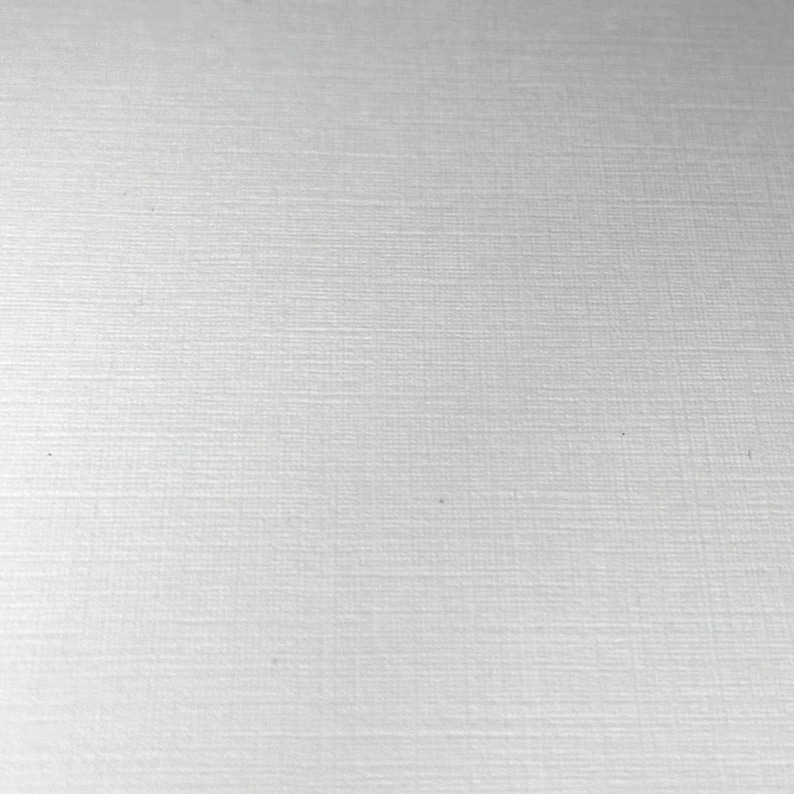 May include: A close-up of a white textured surface. The surface has a subtle, fine grain pattern.