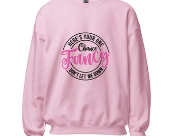 Könnte beinhalten: Hellrosa Sweatshirt mit einem kreisförmigen Aufdruck. Der Aufdruck zeigt den Text "HERE'S YOUR ONE Chance Fancy DON'T LET ME DOWN" in schwarzer und pinkfarbener Glitzerschrift. Das Sweatshirt hat lange Ärmel und einen Rundhalsausschnitt.