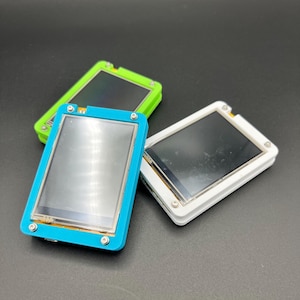 May include: Three small electronic devices with rectangular screens. One has a bright blue frame, another is green, and the third is white. Each device has a dark screen and is secured with small screws.