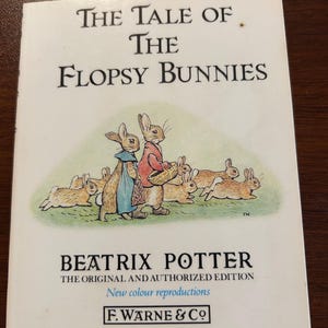 Puede incluir: Un libro de tapa dura titulado "The Tale of the Flopsy Bunnies" de Beatrix Potter. La portada presenta una ilustración de conejos. El texto dice "Nuevas reproducciones en color" y es publicado por F. Warne & Co.