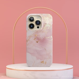 May include: A pink and gold marble phone case for an iPhone 14 Pro Max. The case has a white background with pink and gold marble swirls.