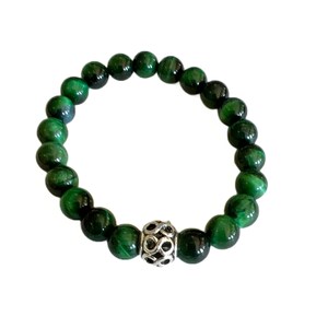 May include: A green tiger's eye beaded bracelet with a silver charm.