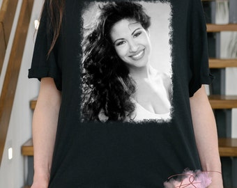 Könnte beinhalten: Schwarzweißfoto einer Frau mit langen, lockigen Haaren. Das Foto ist auf einem schwarzen T-Shirt gedruckt.