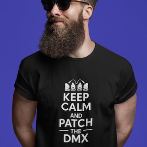 May include: Black t-shirt with the white text "KEEP CALM AND PATCH THE DMX". The shirt features a graphic of three stylized light fixtures above the text. The person in the image is wearing sunglasses and has a beard.