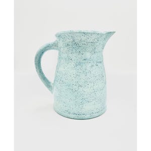 May include: A light blue ceramic pitcher with a speckled glaze. The pitcher has a rounded body and a handle.