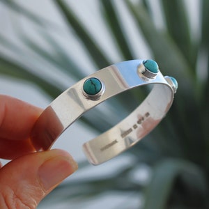 Peut inclure: Bracelet en argent avec quatre pierres turquoise serties dans le métal. Le bracelet est ouvert et porte un poinçon à l'intérieur.